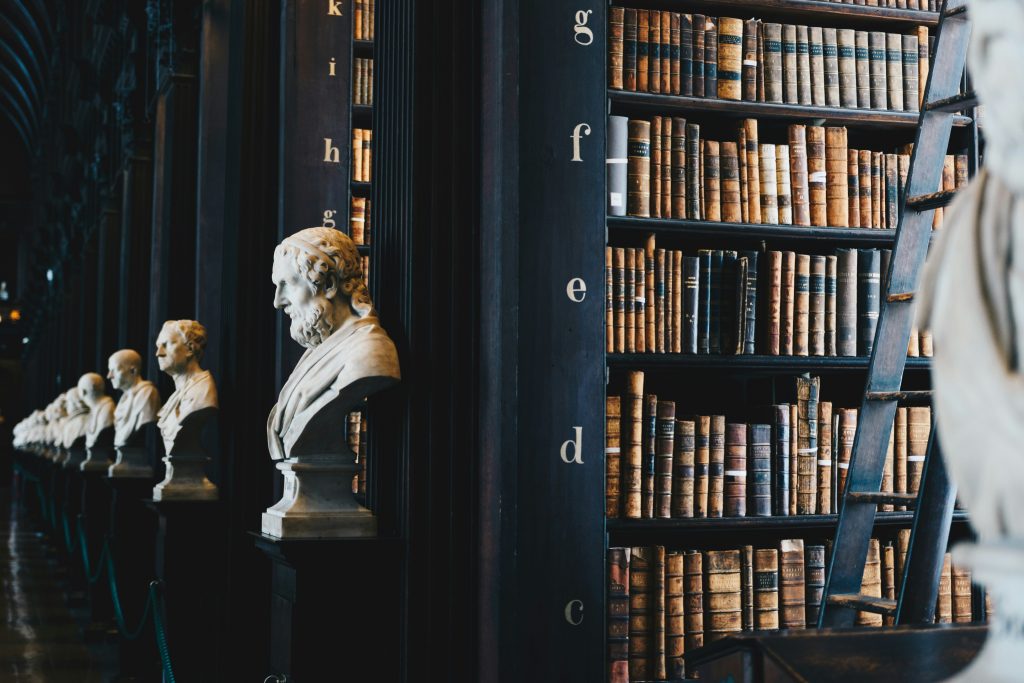 Image of a library with rows of legal books and statues of famous greek orators.